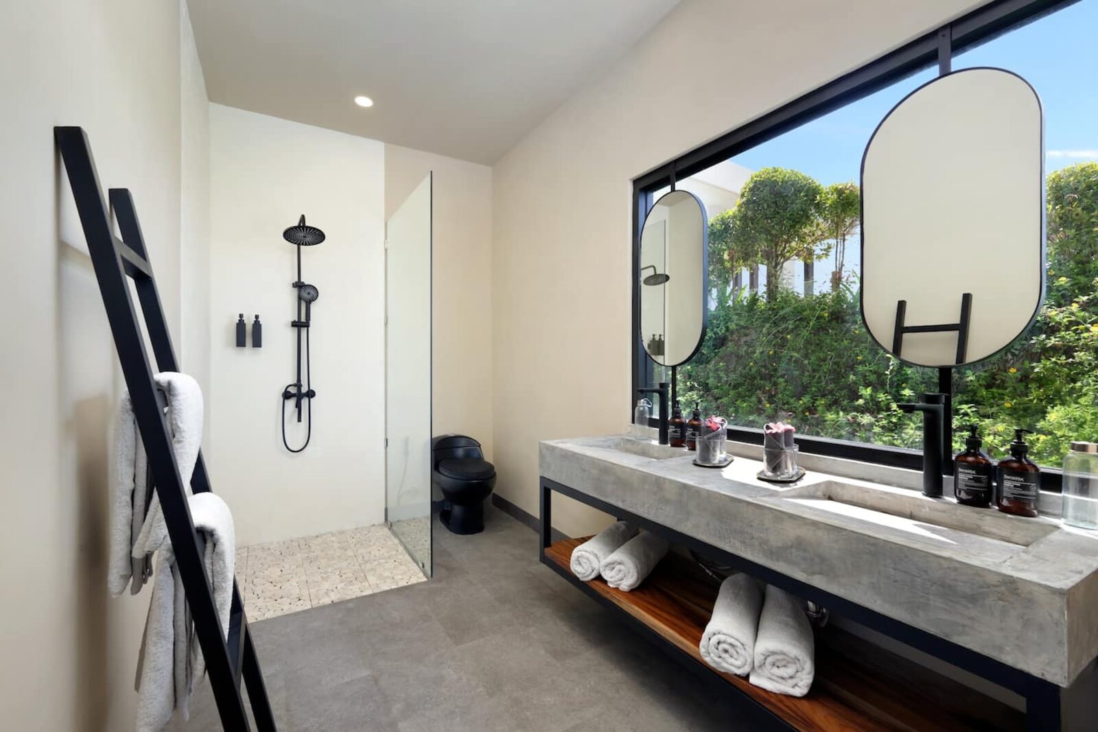 Bathroom with a stone basin, round mirror and a full-height window onto the garden