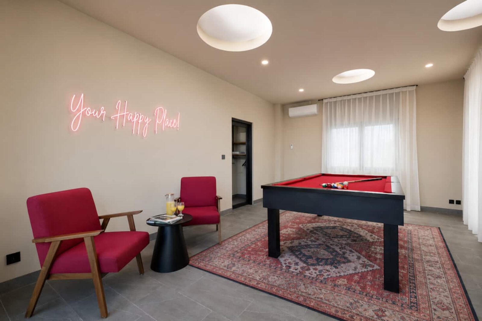 Games room with a pool table, armchairs and a neon sign on the wall