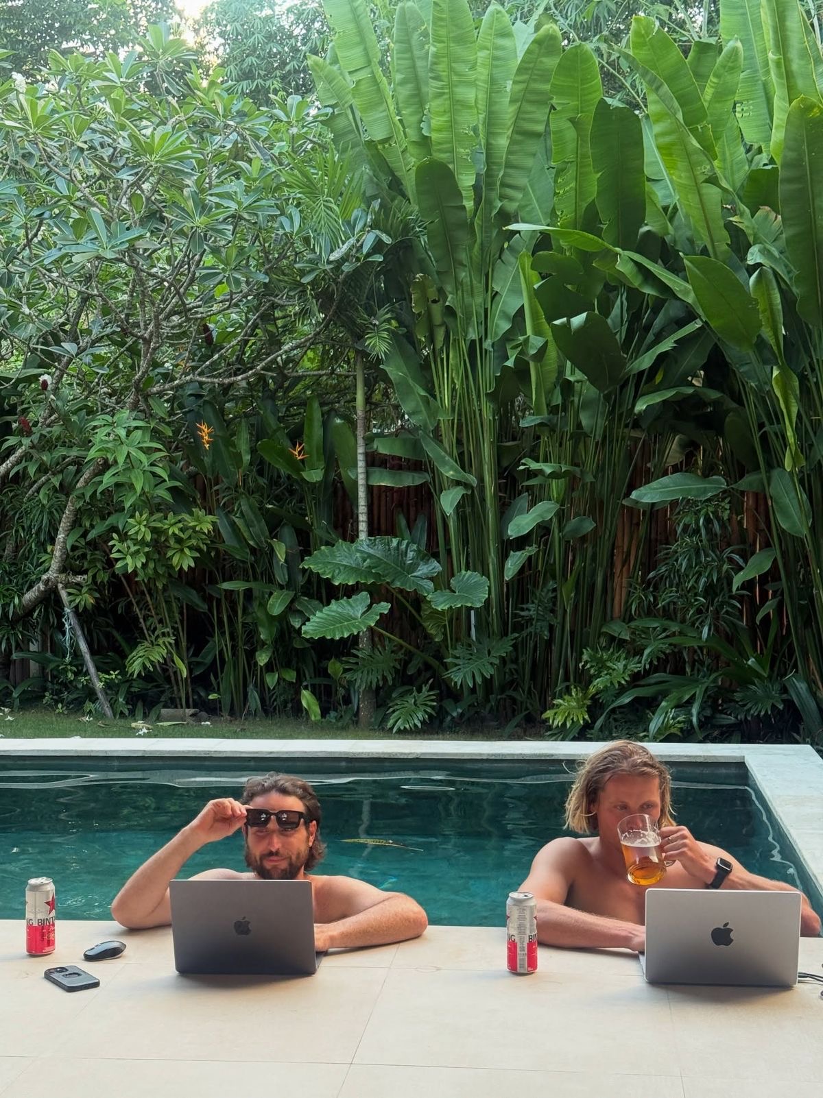 Two founders in deep conversation at an outdoor table, Bali villa in the background