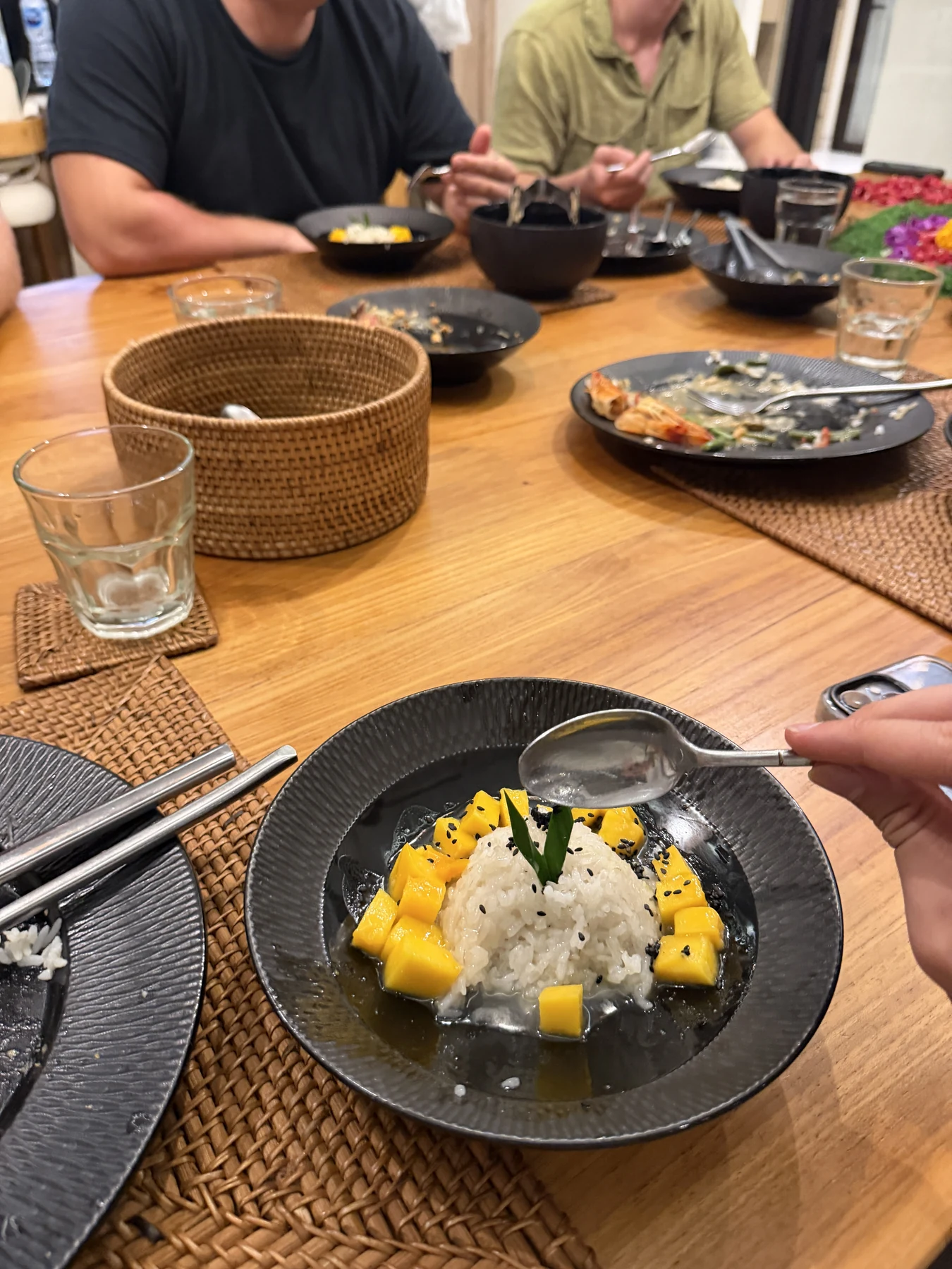 Mango mit Klebreis auf einem schwarzen Teller beim gemeinsamen Abendessen in der Villa auf Bali