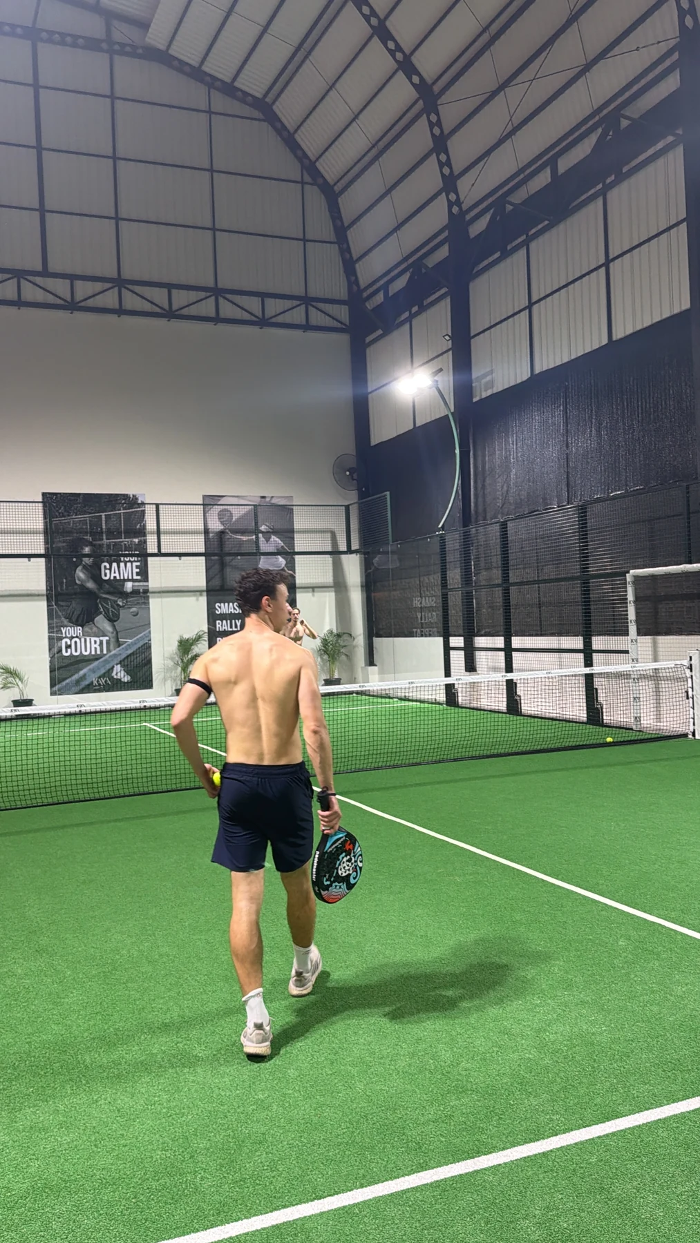 Ein Teilnehmer mit Padelschläger auf dem grünen Court während einer gemeinsamen Runde auf Bali