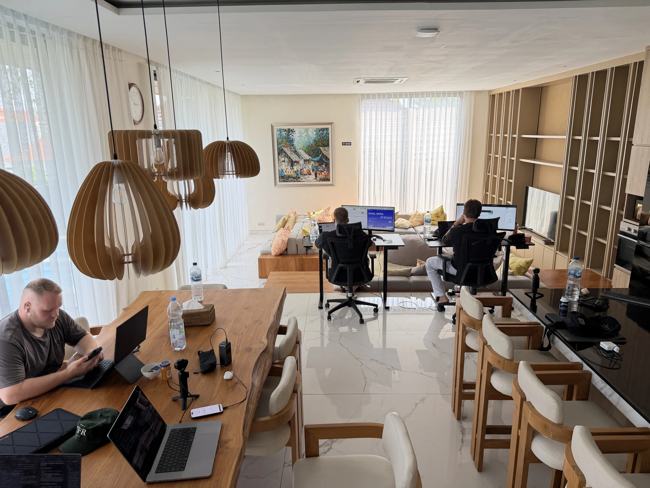 Mehrere Teilnehmer arbeiten an Laptops und Bildschirmen im gemeinsamen Wohnbereich der Villa auf Bali